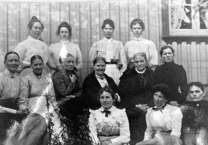Lotten Andersson sitter på marken till vänster. Fotot är tagen omkring 1910.